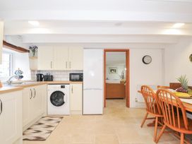 A kitchen with a washing machine and dining table at Henwood Barn in Henwood near Upton Cross