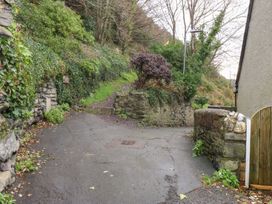 An outdoor pathway with a stone wall and vegetation at Ty'n-Y-Ffynnon Cottage in Barmouth