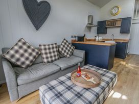 A living room with a sofa and kitchen area at Doe Lodge Nantmel near Rhayader