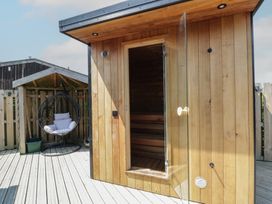 An outdoor area with a sauna and a hanging chair at Tin Shed in Nantmel near Rhayader