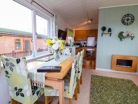 A dining room with a table and flowers at Daffodil Lodge Mullacott near Ilfracombe