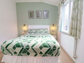 A bedroom with a bed and nightstand at Daffodil Lodge in Mullacott near Ilfracombe