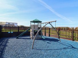 A playground with a play structure and swings at Daffodil Lodge in Mullacott near Ilfracombe