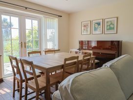 A dining room with a table and piano at 10 The Gardens Rousdon near Lyme Regis