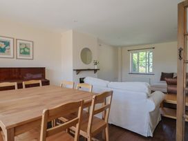A living room with a dining table and piano at 10 The Gardens Rousdon near Lyme Regis