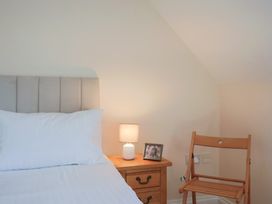 A bedroom with a bed and a nightstand with a lamp at 10 The Gardens in Rousdon near Lyme Regis