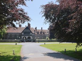 A large building with a driveway and trees at 10 The Gardens in Rousdon near Lyme Regis