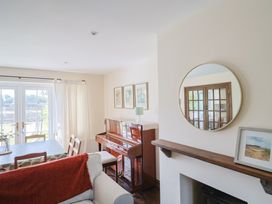 A living room with a piano and dining table at 10 The Gardens Rousdon near Lyme Regis