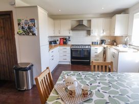 A kitchen with appliances and a dining table at 10 The Gardens in Rousdon near Lyme Regis