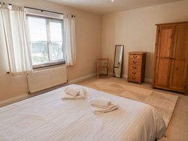 A bedroom with a bed, chair, mirror, dresser, and wardrobe at 10 The Gardens Rousdon near Lyme Regis