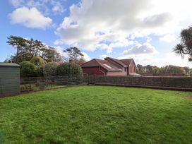 A garden with grass, a shed, and trees at 10 The Gardens Rousdon near Lyme Regis