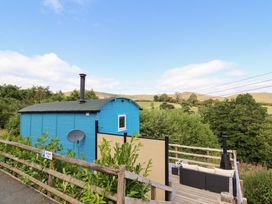 A hut and deck with trees in the background at Cuckoo at Wild Valley Huts Llanrhaeadr-Ym-Mochnant