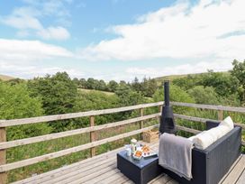 An outdoor deck with furniture and a chiminea at Cuckoo at Wild Valley Huts Llanrhaeadr-Ym-Mochnant