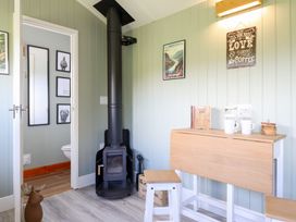 A room with a wood stove and a table with coffee cups at Cuckoo at Wild Valley Huts Llanrhaeadr-Ym-Mochnant
