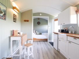 A kitchen area with a table and stools at Cuckoo at Wild Valley Huts Llanrhaeadr-Ym-Mochnant