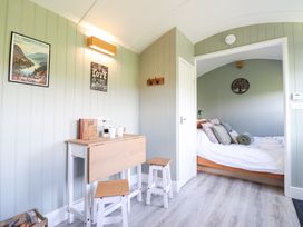 A bedroom with a bed and stools at Cuckoo at Wild Valley Huts in Llanrhaeadr-Ym-Mochnant
