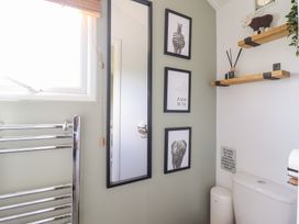 A bathroom with a toilet, towel rail, and wall art at Cuckoo at Wild Valley Huts Llanrhaeadr-Ym-Mochnant