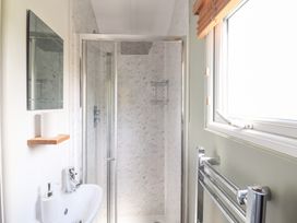 A bathroom with a shower and sink at Cuckoo at Wild Valley Huts Llanrhaeadr-Ym-Mochnant