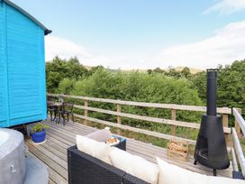 An outdoor patio with a blue cabin, table and chairs at Cuckoo at Wild Valley Huts Llanrhaeadr-Ym-Mochnant
