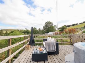 A deck with outdoor furniture and a hot tub at Cuckoo at Wild Valley Huts in Llanrhaeadr-Ym-Mochnant