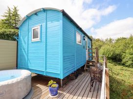 A blue hut with a hot tub and stairs in an outdoor area at Cuckoo at Wild Valley Huts Llanrhaeadr-Ym-Mochnant