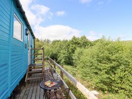 An outdoor area with a blue cabin and a table with snacks at Cuckoo at Wild Valley Huts Llanrhaeadr-Ym-Mochnant