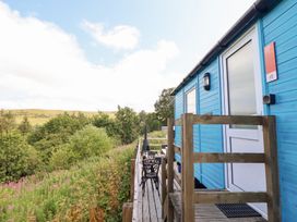 A blue hut with a deck and outdoor chair at Cuckoo at Wild Valley Huts Llanrhaeadr-Ym-Mochnant