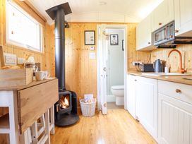 A kitchen with a fireplace and wooden cabinets at Red Kite at Wild Valley Huts Llanrhaeadr-Ym-Mochnant