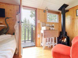 A living room with a wood stove and a table at Red Kite at Wild Valley Huts in Llanrhaeadr-Ym-Mochnant