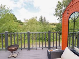 An outdoor area with a deck, barbecue, and seating at Red Kite at Wild Valley Huts, Llanrhaeadr-Ym-Mochnant