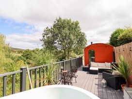 An outdoor deck with seating and a hut at Red Kite at Wild Valley Huts Llanrhaeadr-Ym-Mochnant