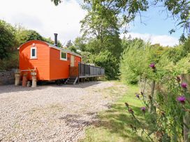 An outdoor view of an orange shed on gravel at Red Kite at Wild Valley Huts Llanrhaeadr-Ym-Mochnant