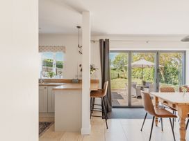 A kitchen with a table and chairs overlooking the outdoor seating area at Tokenhill Cottage in Piddletrenthide