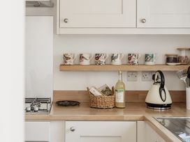 A kitchen with a shelf of cups and a kettle at Tokenhill Cottage in Piddletrenthide