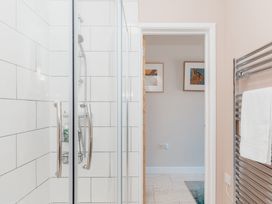 A shower with glass doors and a towel warmer at Tokenhill Cottage in Piddletrenthide