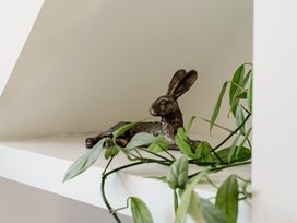 A rabbit sculpture and plant on a shelf at Tokenhill Cottage in Piddletrenthide