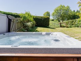 A hot tub with grass and trees in the background at Tokenhill Cottage in Piddletrenthide