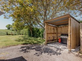 An outdoor grill and chairs in a shelter at Tokenhill Cottage in Piddletrenthide