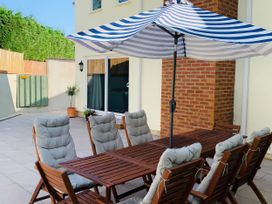 An outdoor patio area with a wooden table and chairs at Brooklands in Uplyme