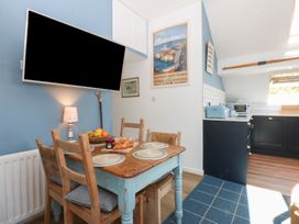A kitchen with a dining area and television at Borth Arian Boat House in Holyhead