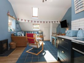 A living room with a sofa and kitchen area at Borth Arian Boat House in Holyhead