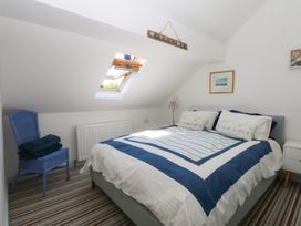 A bedroom with a bed, chair and lamp at Borth Arian Boat House in Holyhead