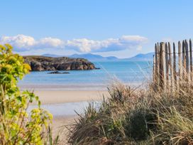A beach view with water, sand, and rocks at Borth Arian Boat House in Holyhead