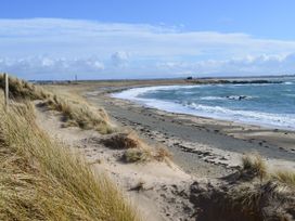 A beach with sand and grass along the shore at Borth Arian Boat House Rhoscolyn