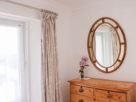 A bedroom with a mirror and flowers on a chest of drawers at 2 Channel View Salcombe