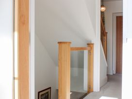 A staircase with a glass panel and wooden handrail at 2 Channel View Salcombe