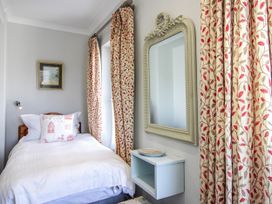A bedroom with a single bed and decorative curtains at 2 Channel View, Salcombe