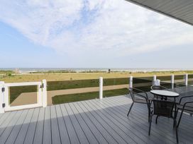 An outdoor area with a table and chairs overlooking the beach at Bonny Bay Wilsthorpe near Bridlington