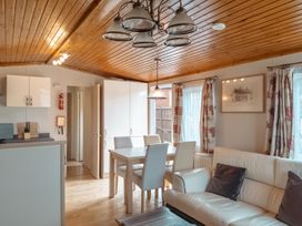 A living room with a kitchen area and a dining table at Willow in Swanage