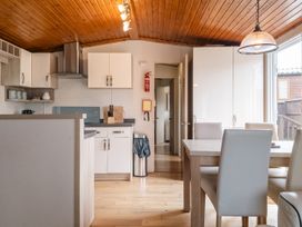 A kitchen with cabinets and a dining table at Willow in Swanage